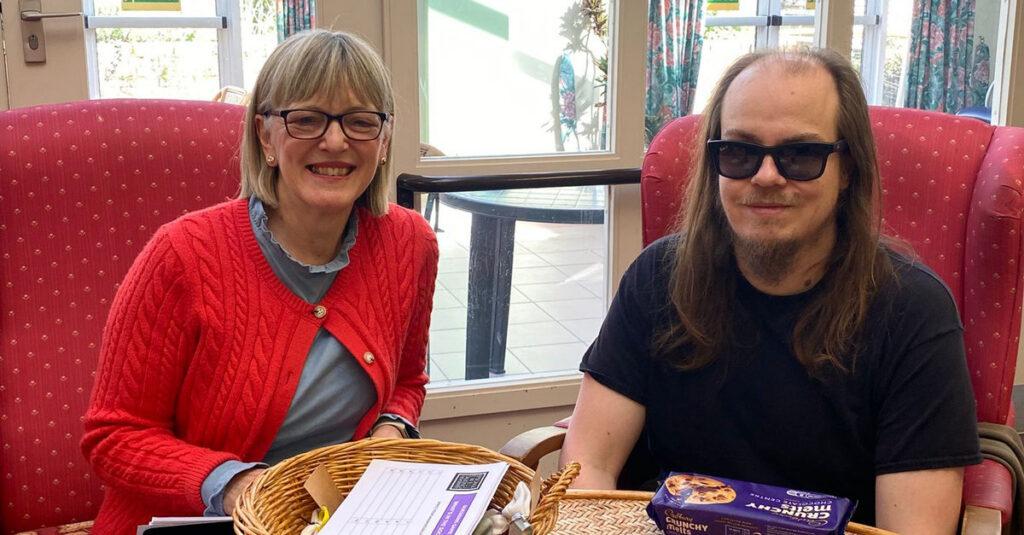 A talking newspaper volunteer sat next to a blind member of the Banstead Club